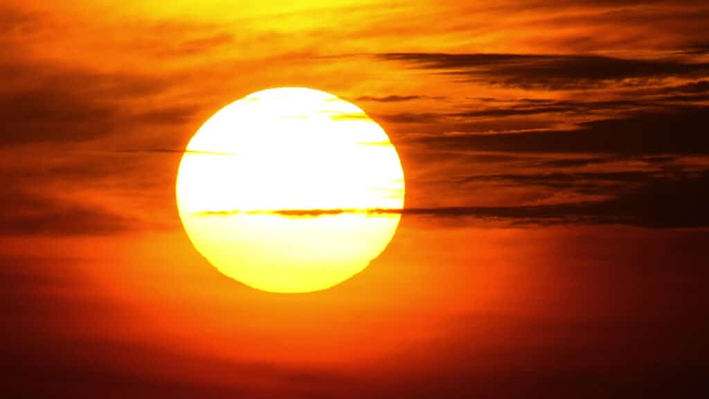 bright orange sun in the sunset sky with clouds